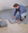 Contractors installing basement subfloor tiles and matting on a concrete basement floor in Cormack, Newfoundland and Labrador
