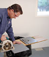 installing a waterproof vapor barrier on a basement floor to prepare for basement carpeting in a Deer Lake home